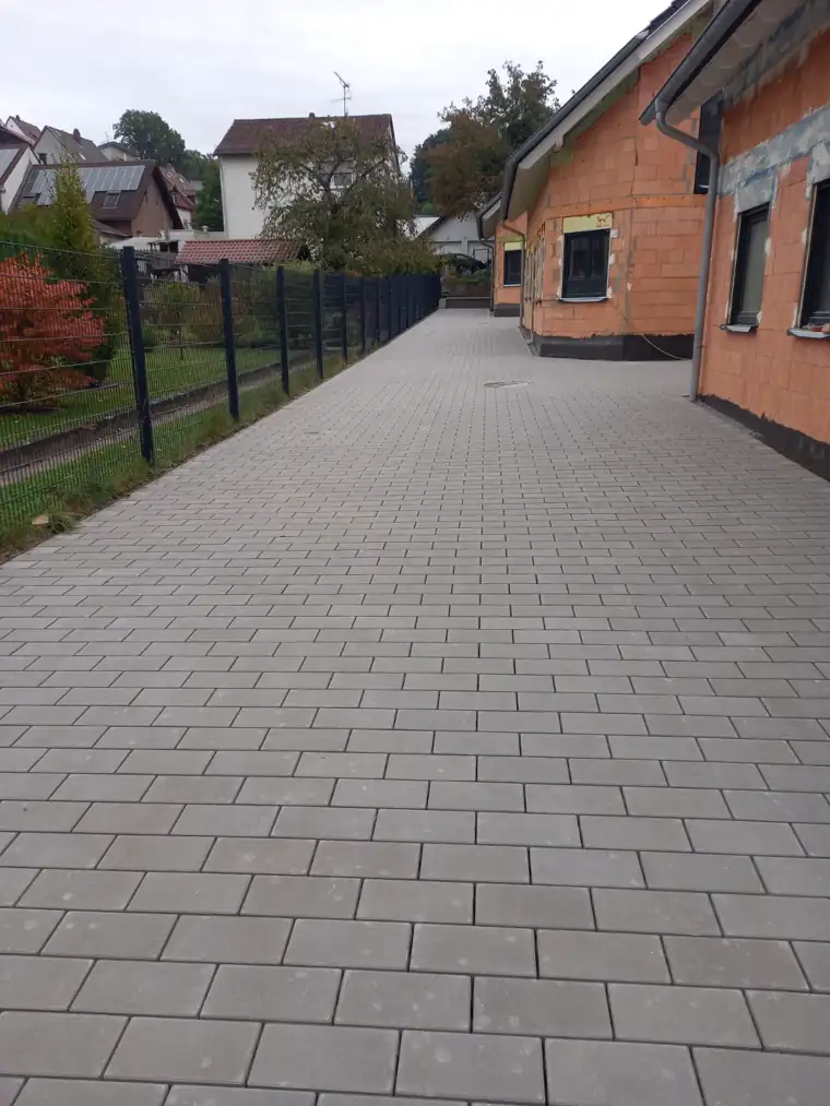 Lange gepflasterte Hofeinfahrt entlang eines Klinkerhauses