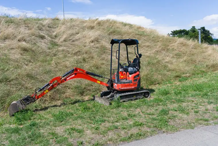 Roter Minibagger auf einer Wiese