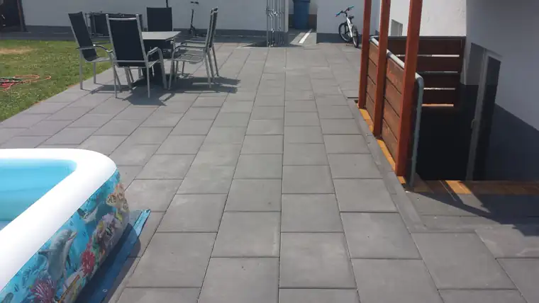 Große Terrasse mit anthrazitfarbenen Platten neben einem Holzsichtschutz